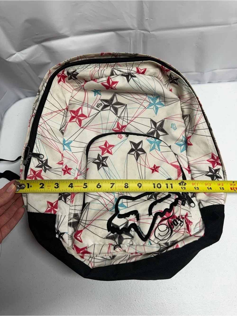 Fox Racing white polyester backpack with red, blue, and black stars and lines
